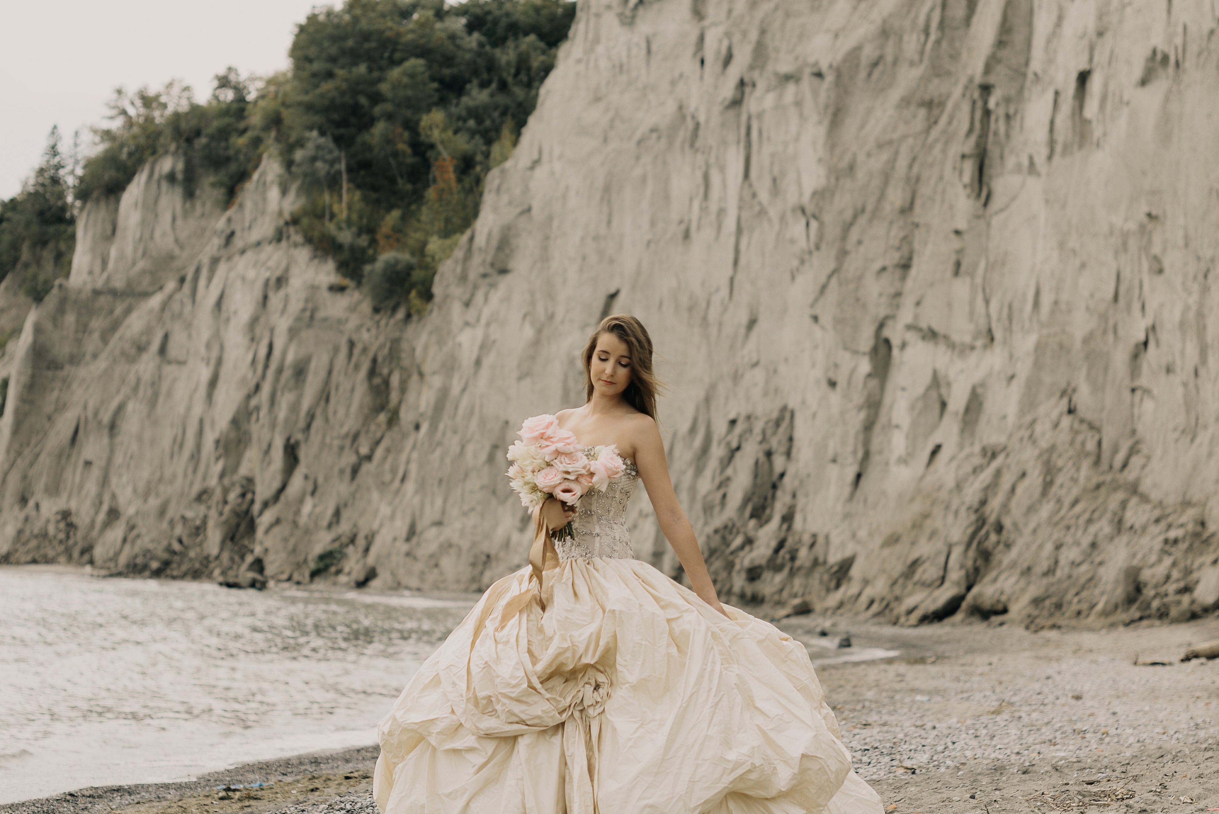 Bride in wedding dress by cliffs and beach