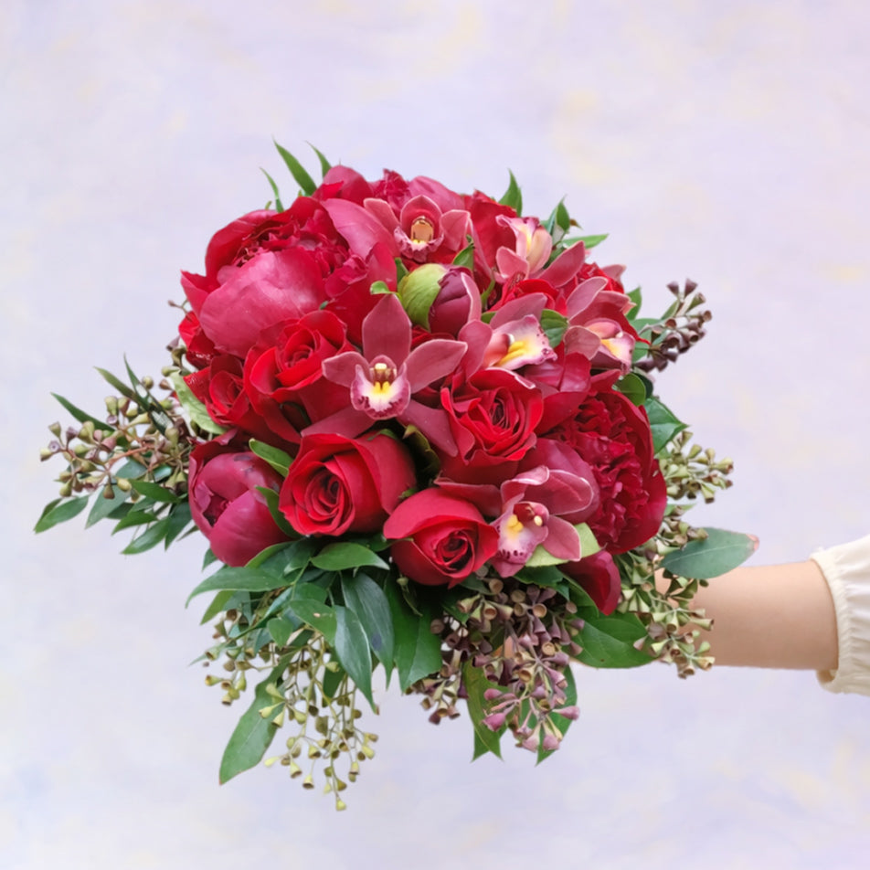 Bouquet of red flowers with green leaves on a light background