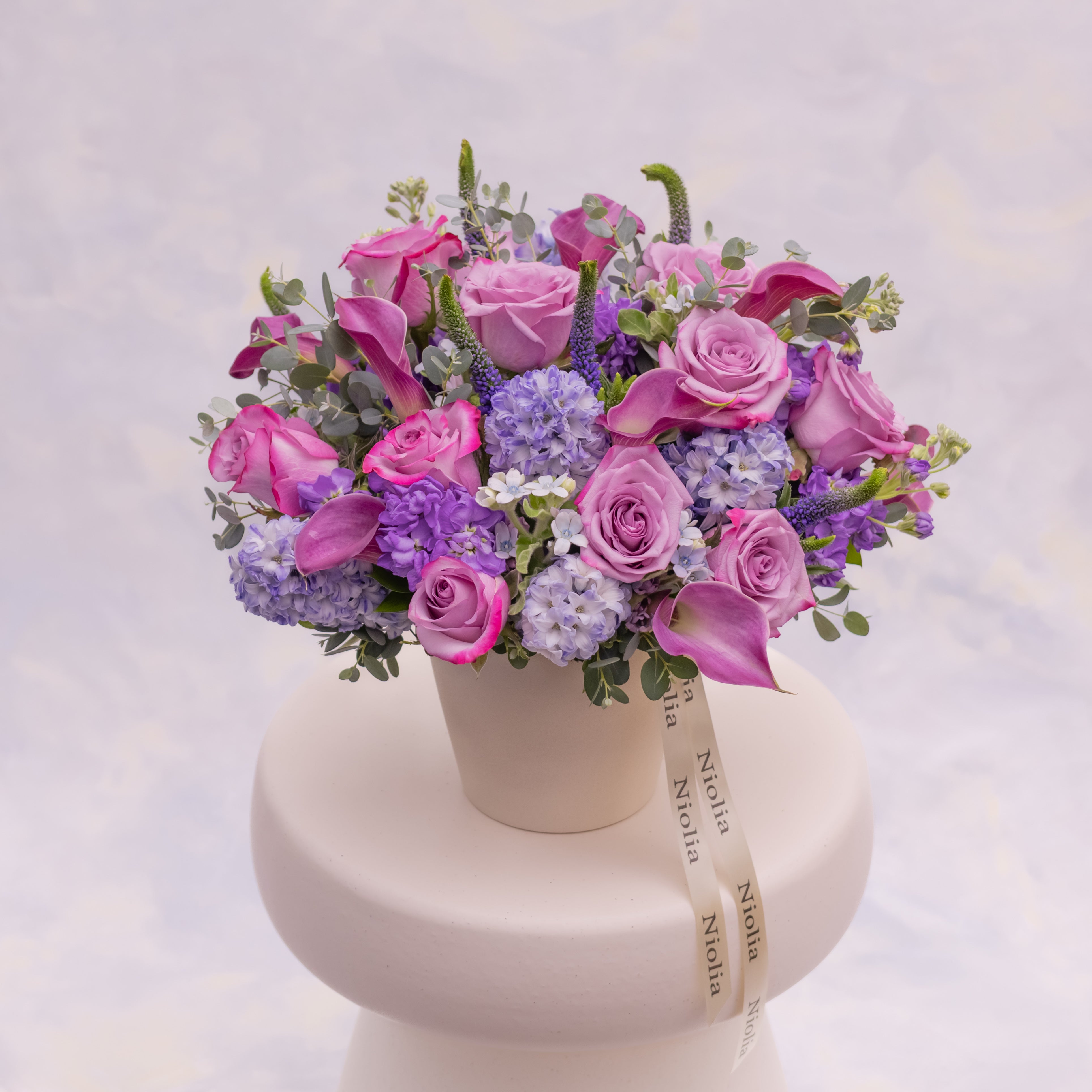 Lavender garden style flower arrangement in cream ceramic vase available for flower delivery in San Francisco. 
